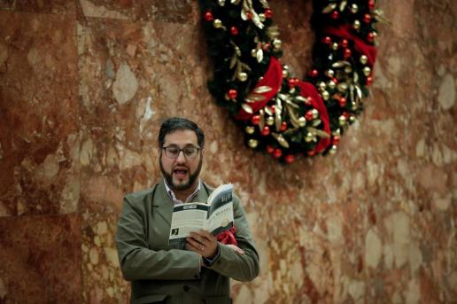 A man reads out load from the book "Night" by Elie Wiesel while standing in the lobby at Trump Tower in New York